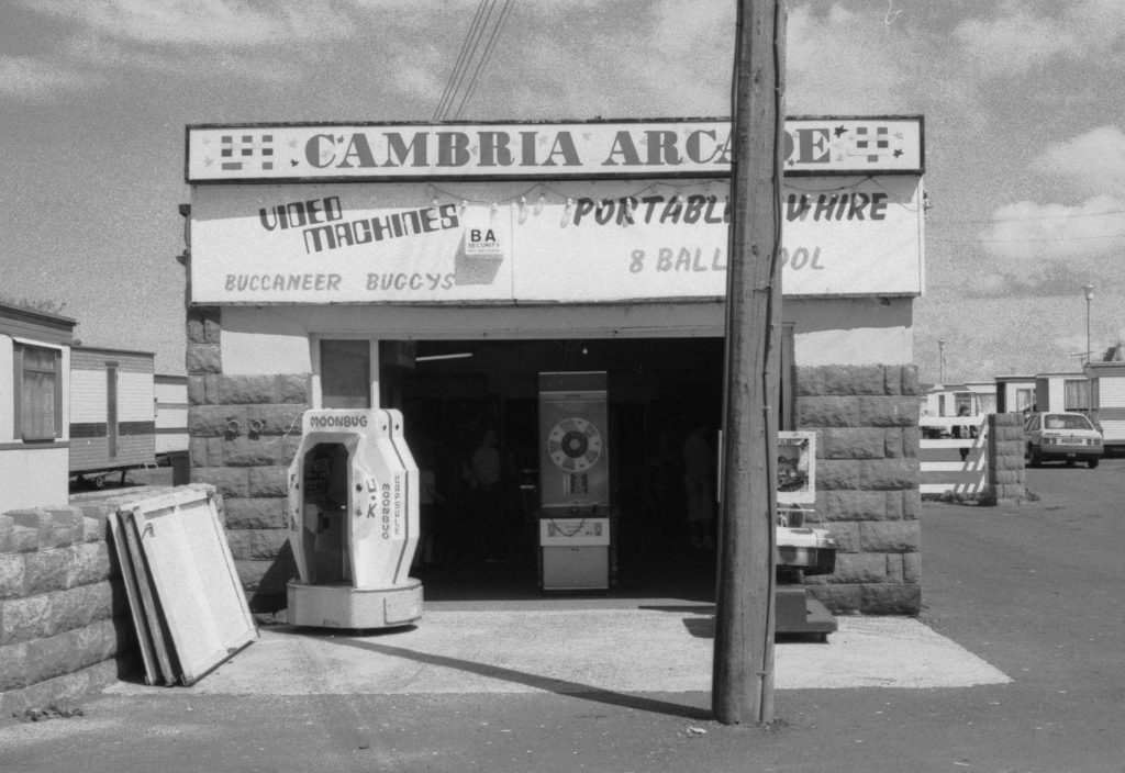 Cambria Arcade, Towyn, North Wales by Stephen Clarke. Black and white photograph of a small arcade front on a caravan park.