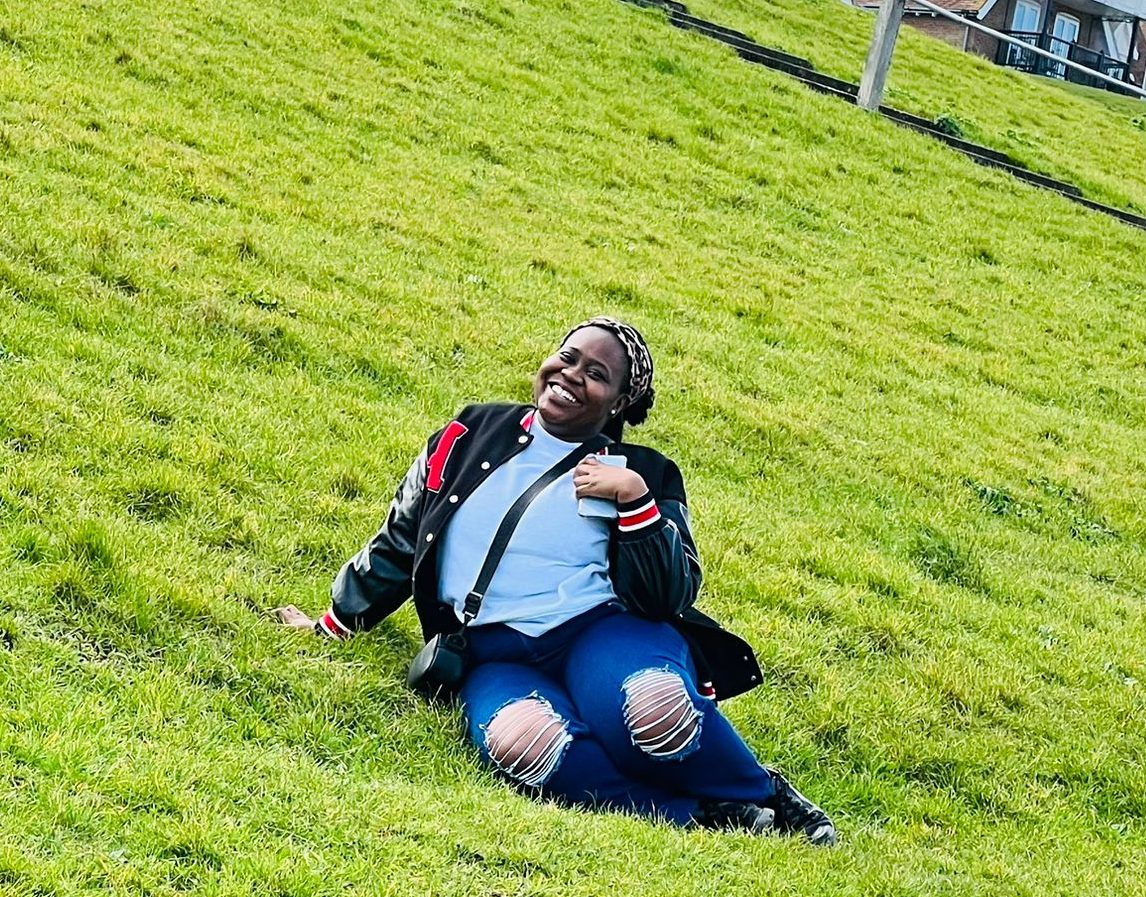 Chido sitting on a bright green and grassy hill