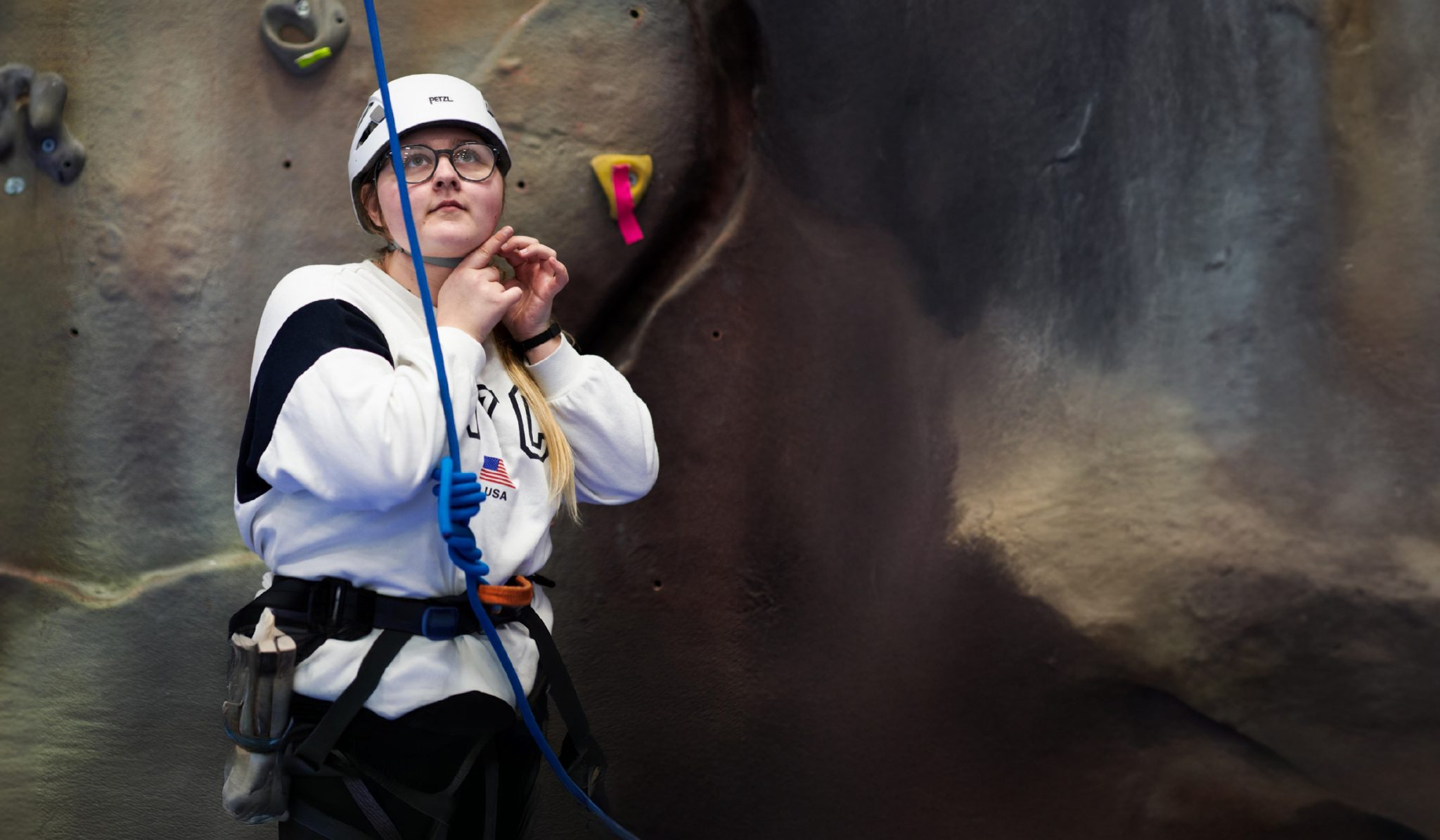 Student standing next to climbing wall