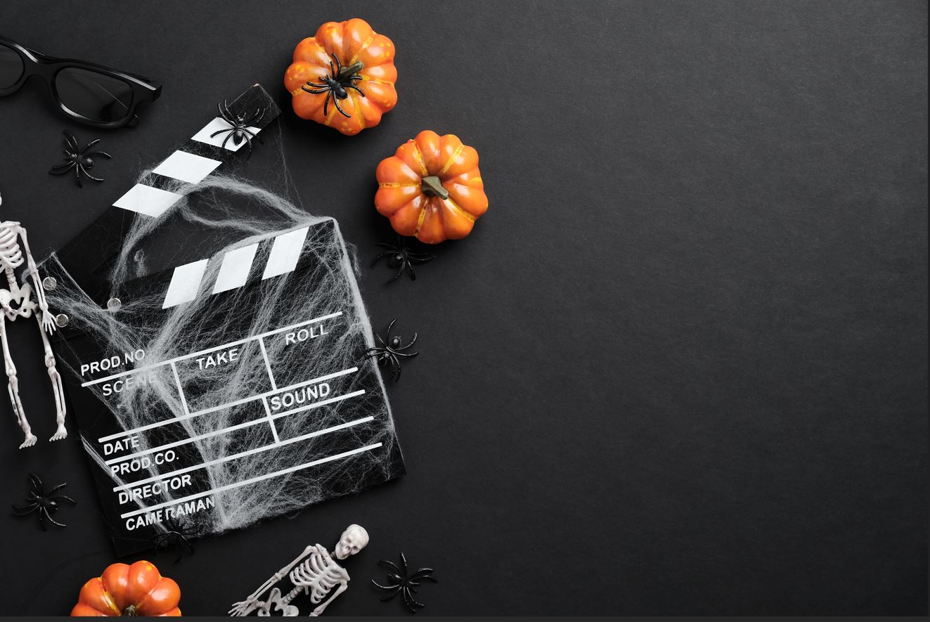 A clapperboard with skeletons and pumpkins on a black background