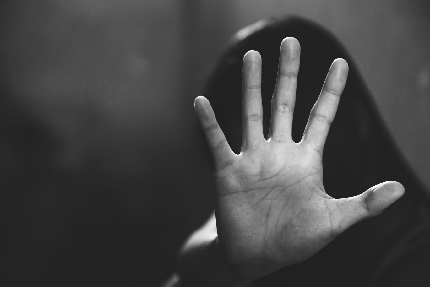 Shutterstock: A women's raising her hand as a sign of domestic abuse