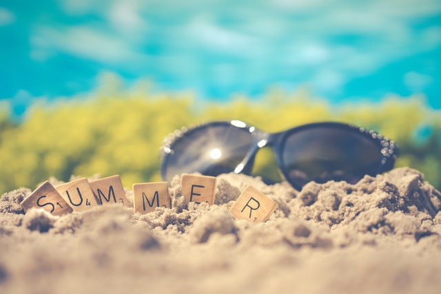 Sunglasses on beach with "summer" spelled out with Scrabble tiles