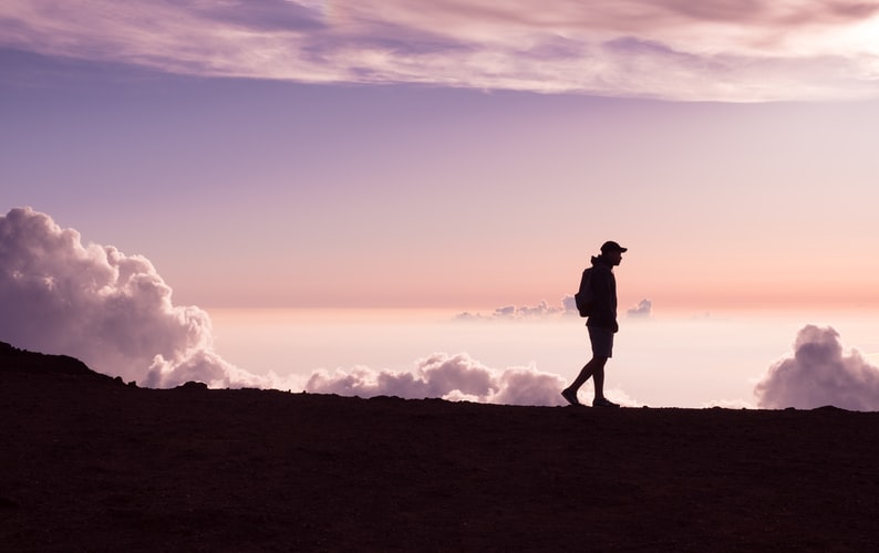 silhouette of a guy walking along a mountain ridge 