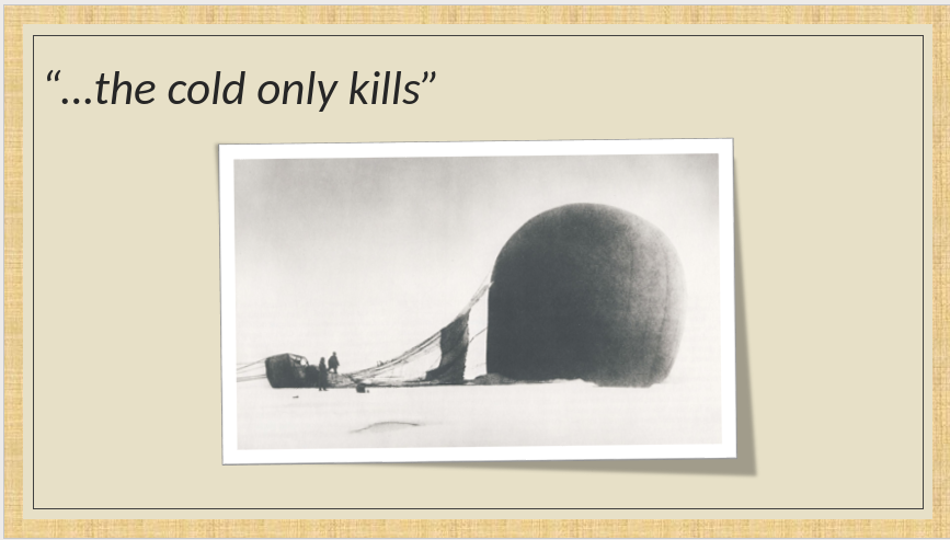 A crashed hot air balloon lying in the snow with men standing next to it.