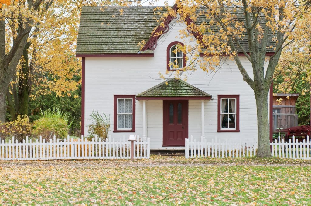 white two storey house with a white picket fence