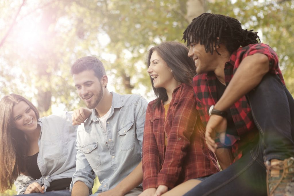 Group of four twenty-something's sitting outside having a laugh and a god time