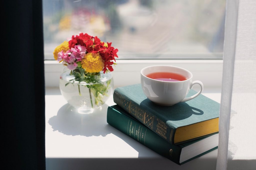 calming window sill view with books, tea and flowers