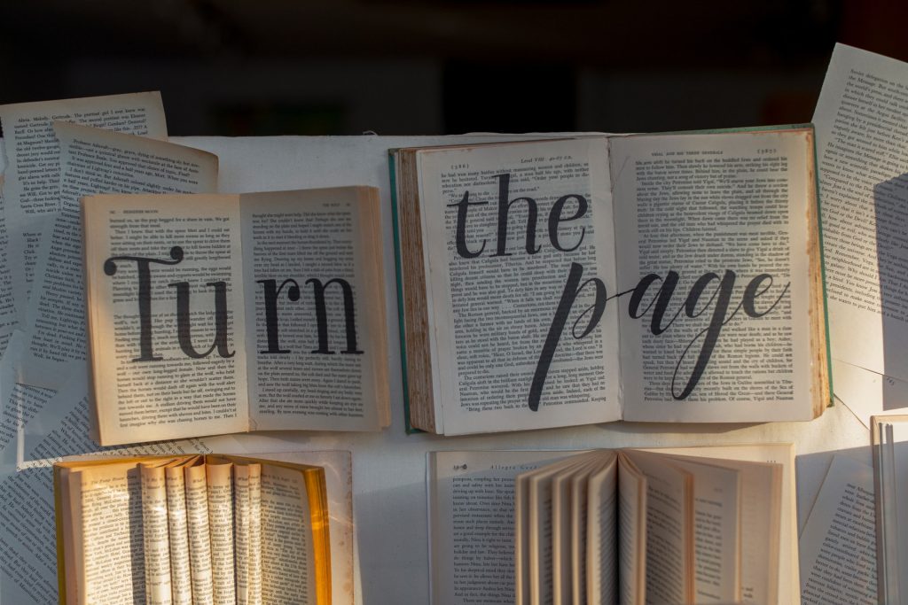 A collection of open books with 'turn the page' written in big letters across them