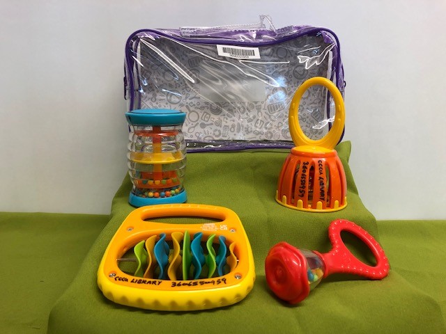 Clear plastic container with four very different, brightly coloured rattles or shakers. 
