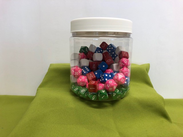 A clear container with a screw lid containing a wide selection of dice