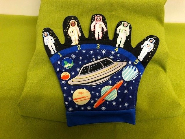 A glove with a spaceship, planets and stars on the palm, with a individual astronaut on each of the fingers.