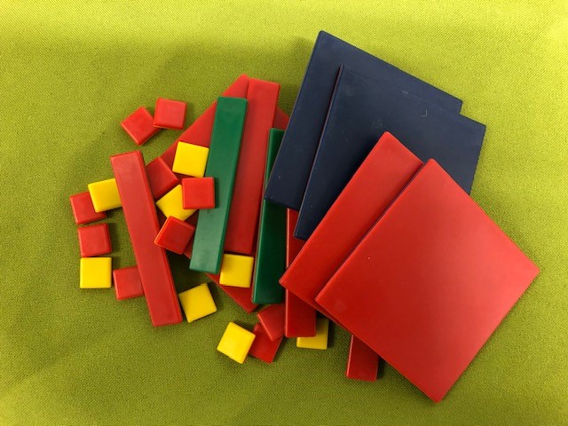 an assortment of hard plastic algebra tiles large squares, small squares and lines.