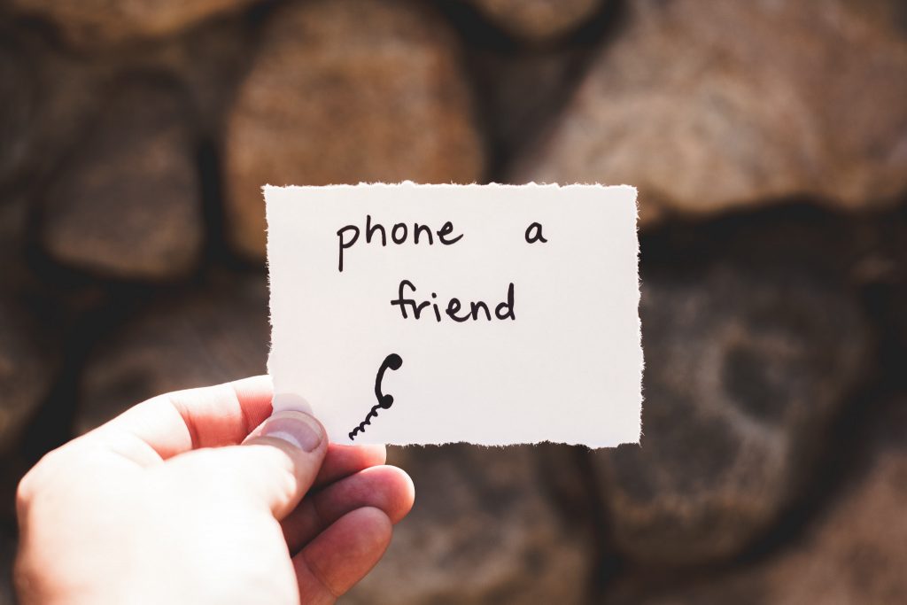 Photo of a hand holding a note that reads ‘phone a friend’.