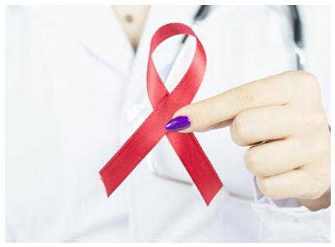 A hand with one purple fingernail holds a red AIDS ribbon