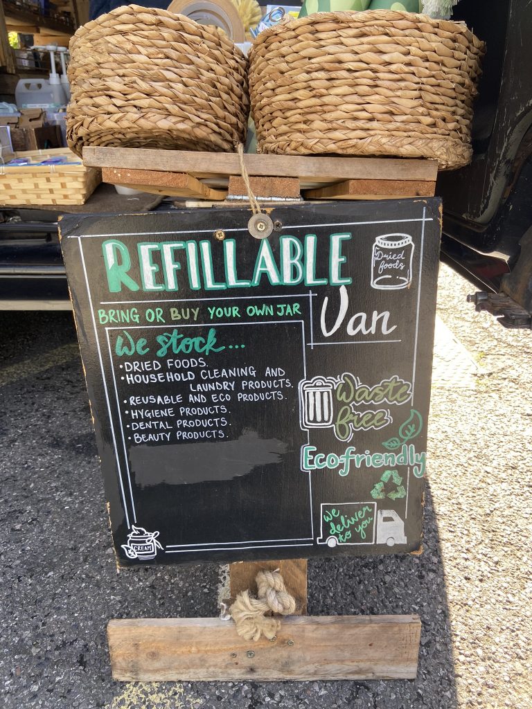 Sign displayed outside the Refillable Van displaying various products for sale. 