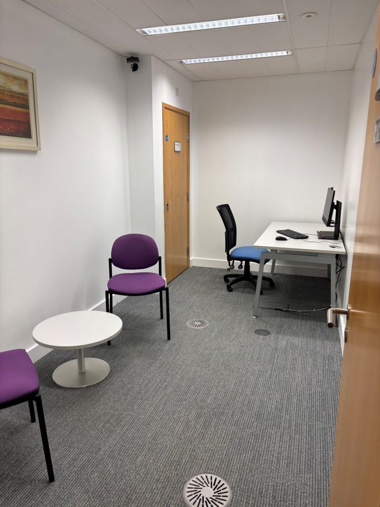 A small study room with a desk and PC and a small break out space for a pair.