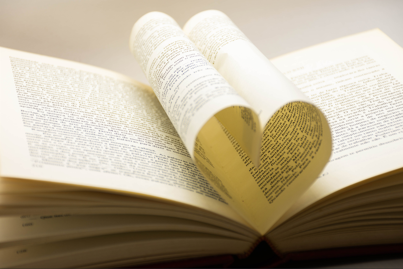 Photo of an open book with a love heart shaped from the pages.
