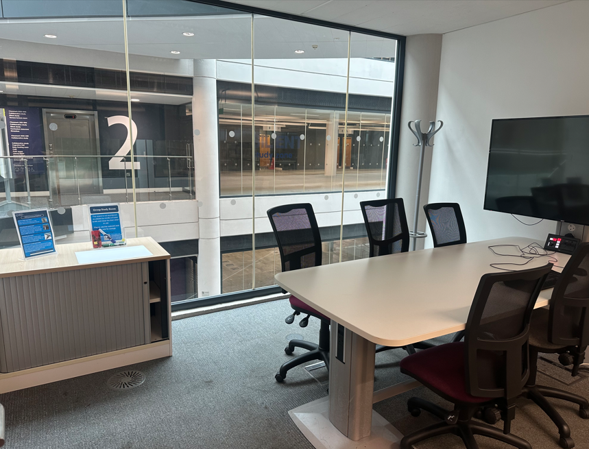 Photograph of Group Study Room with desk, large screen and cupboard.