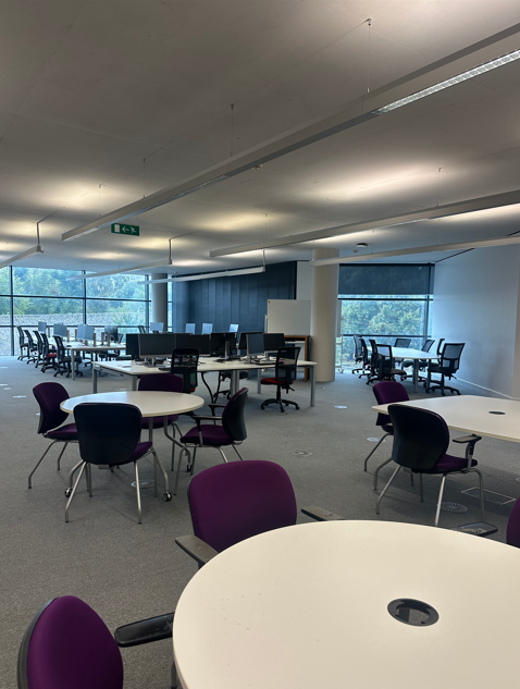 Photograph of the front of collaborative floor with Tables, chairs and PCs
