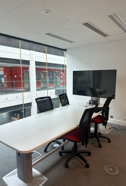The third floor group study room with desk, chairs and large screen.