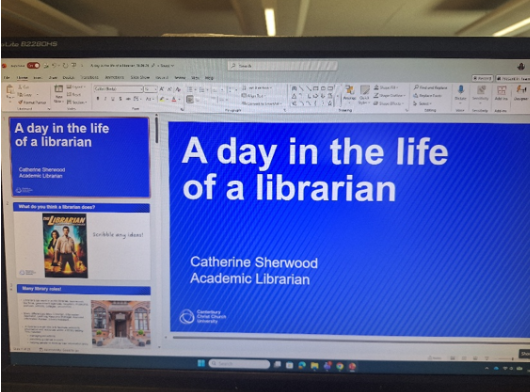A picture of a computer screen with a powerpoint slide, consisting of a blue background and white text saying 'A day in the life of a librarian.'