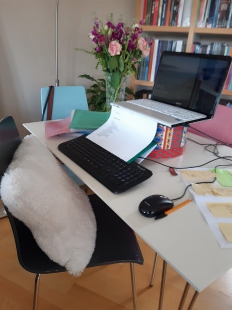 Laptop being raised by a box and a notebook being used as a document holder. 