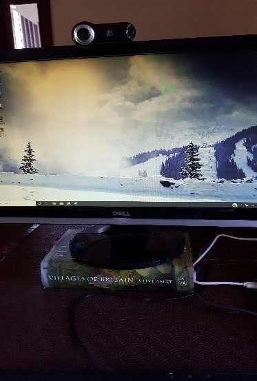 Book called 'Villages of Britain' placed underneath computer screen to raise it