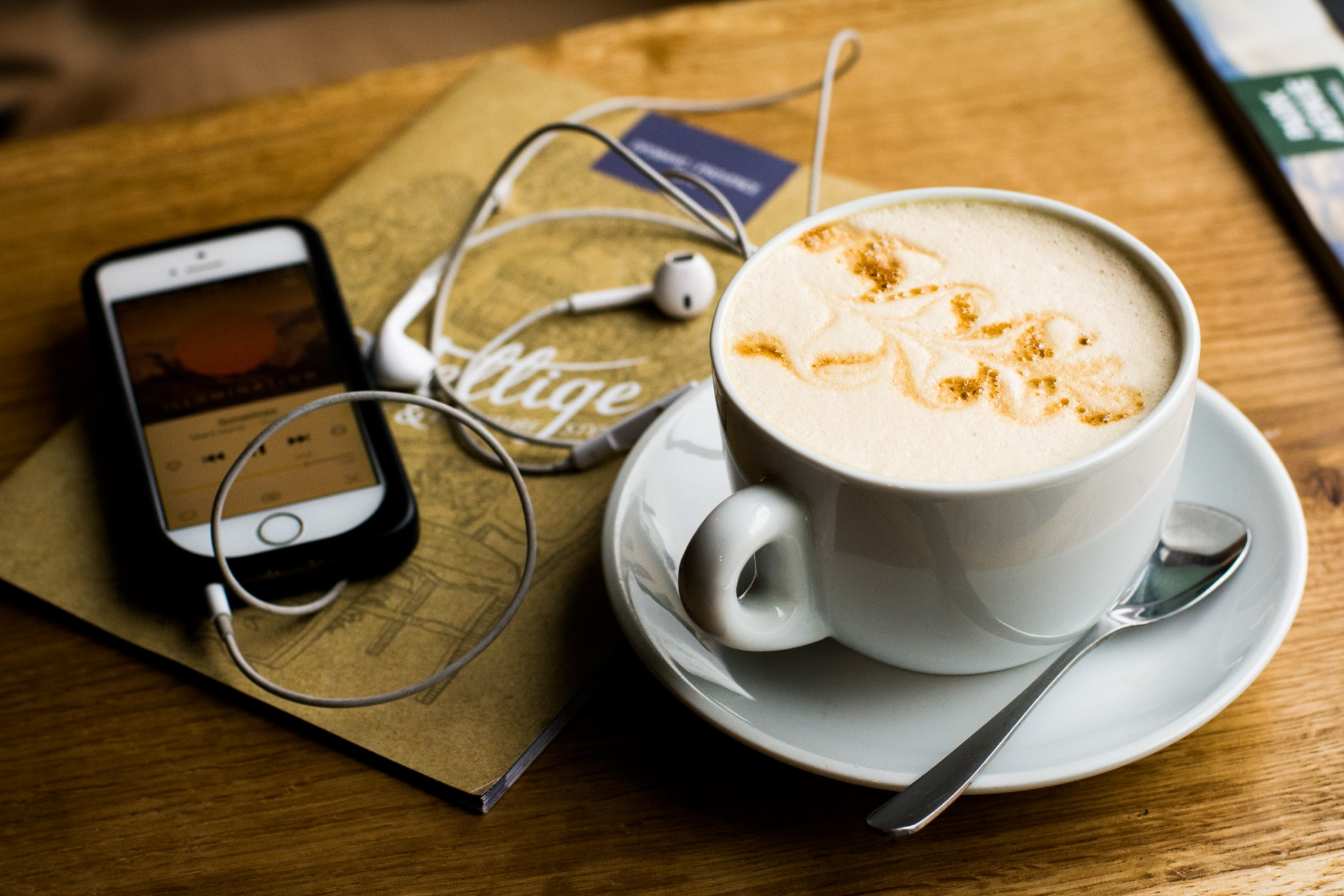 Smartphone with headphones and a cup of coffee on a table