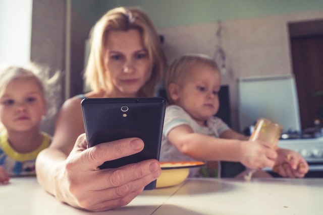 Mothers working on phone with her two children