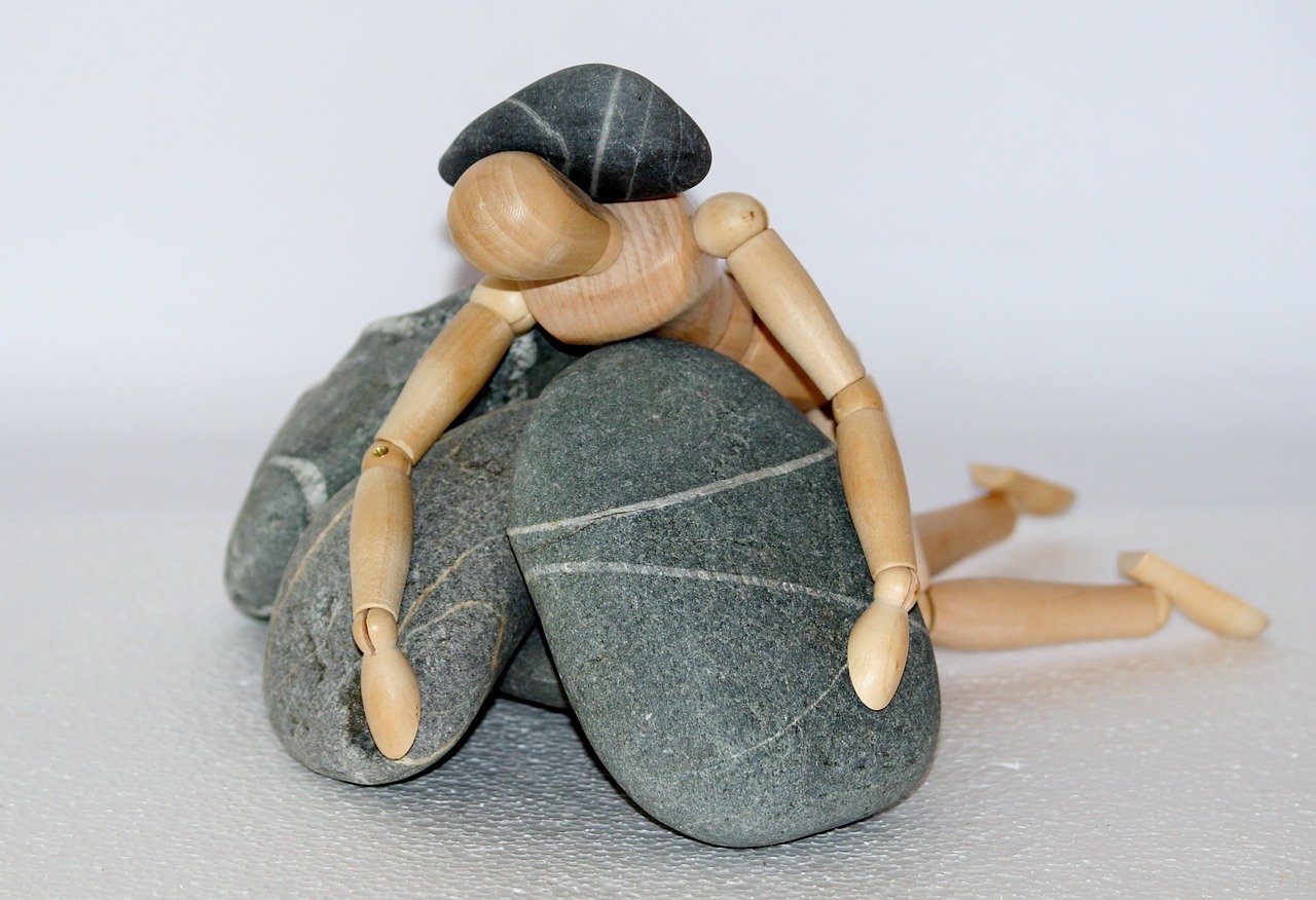 wooden figure trapped under stones
