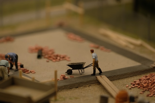 A miniature scene of a building site with a worker pushing a wheelbarrow