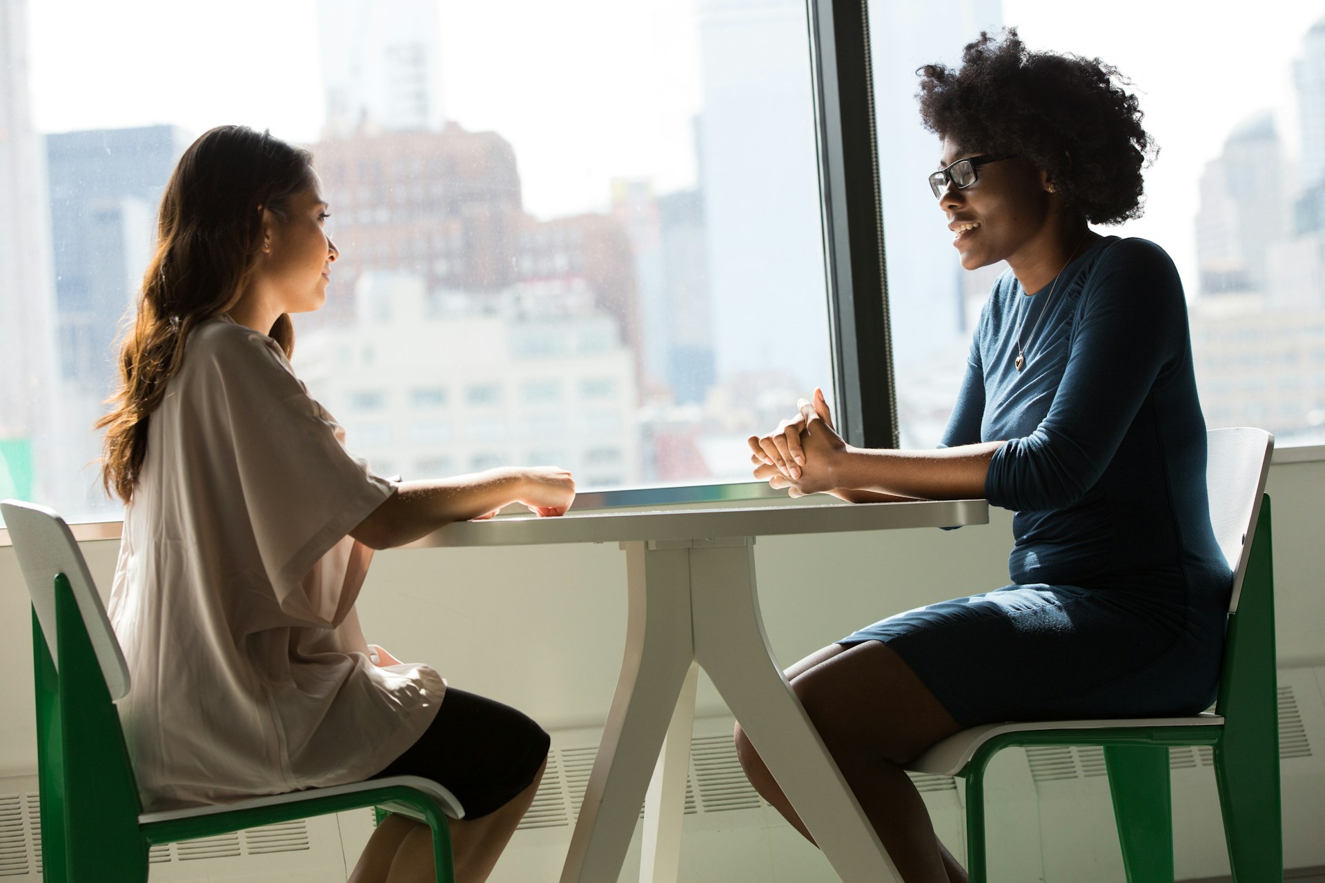two women sitting at a table together having a conversation