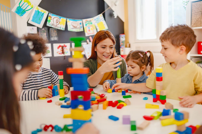 Teacher with children in a classroom playing with building bricks