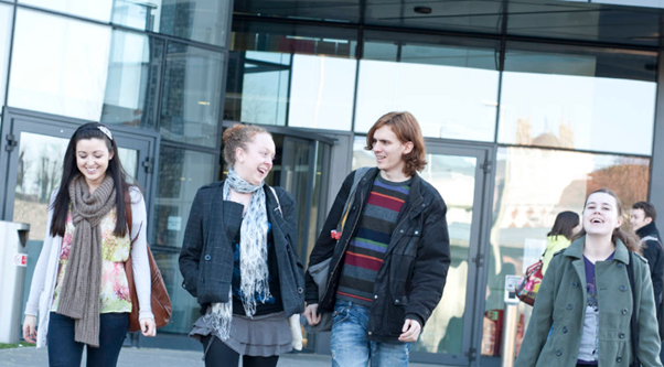 Four students walking out of the front of Augustine House Library